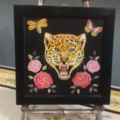 Scagliola dipinge un felino con fiori e insetti