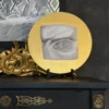 Sottopiatto rotondo La Visione in vetro grafite con dettagli in foglia d'oro